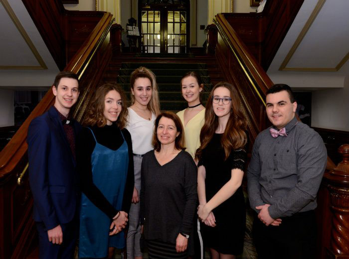 Six étudiants et une enseignante au pied d'un escalier à l'intérieur du parlement de Québec