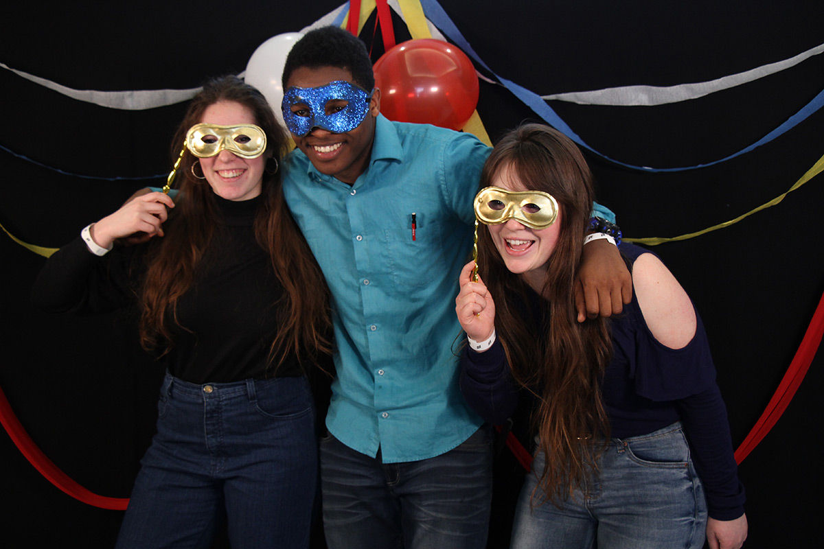 Trois étudiants dans une ambiance festive avec des demi-masques