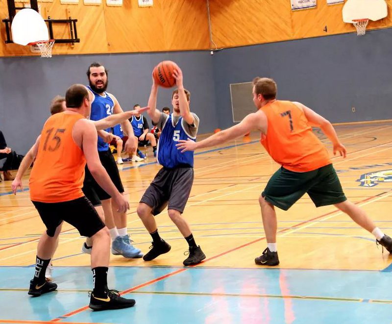 Quatre joueurs de basketball masculin s'affrontent dans un gymnase