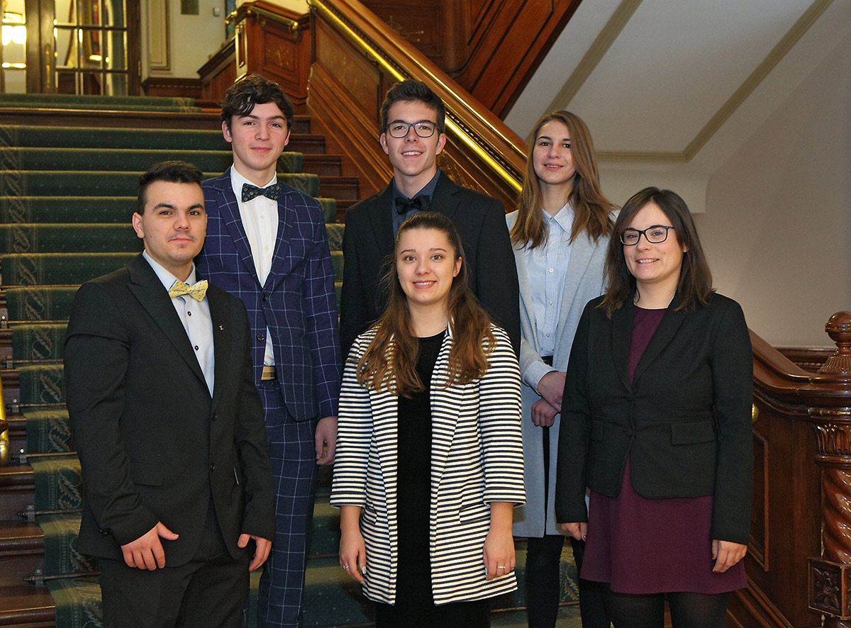 Cinq étudiants participant au Forum jeunesse avec l'enseignante accompagnatrice, devant un escalier au parlement de Québec