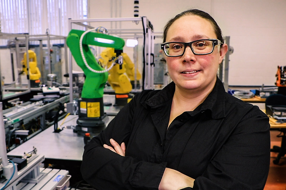 Annie Fiset devant un robot-outil dans un laboratoire d'électronique