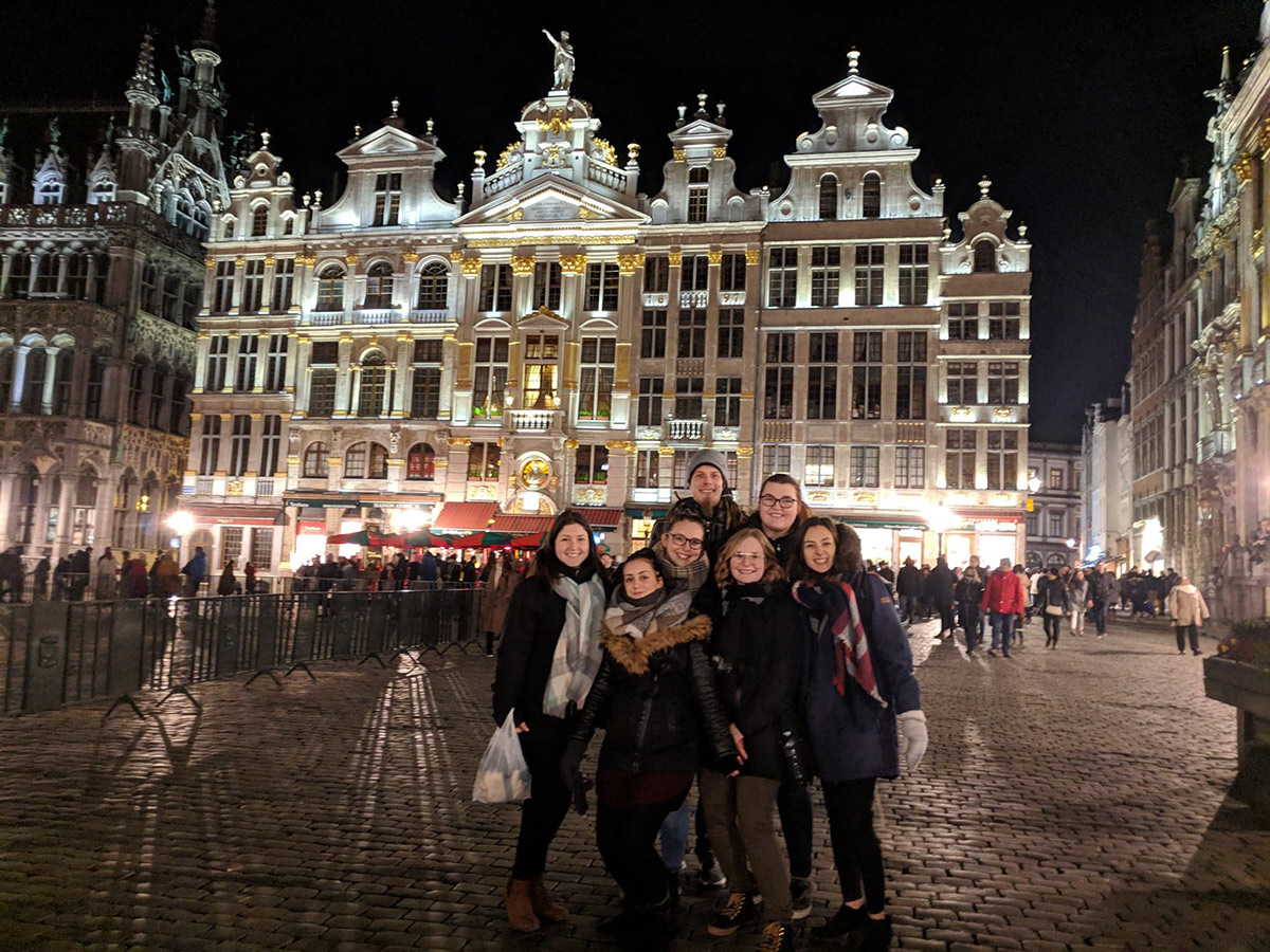 Groupe d'étudiant d'Éducation spécialisée devant un bâtiment historique en Belgique la nuit