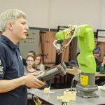 Un enseignant manipule un robot-outil devant des élèves dans un laboratoire d'électronique