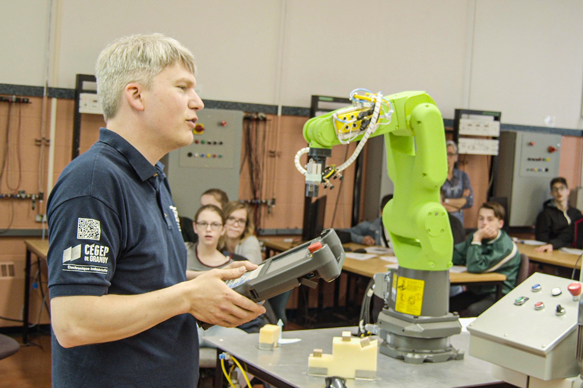 Un enseignant manipule un robot-outil devant des élèves dans un laboratoire d'électronique