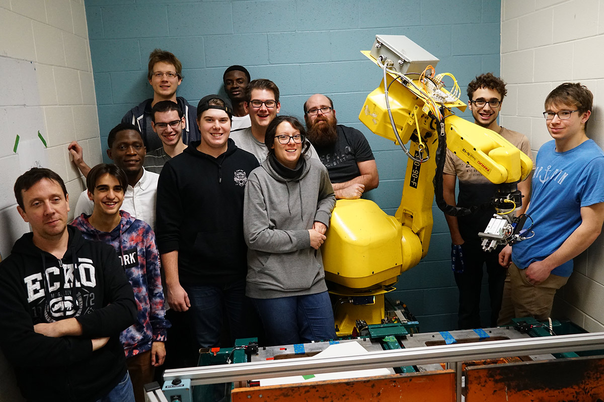 Groupe d'étudiants dans une salle avec un bras robotisé