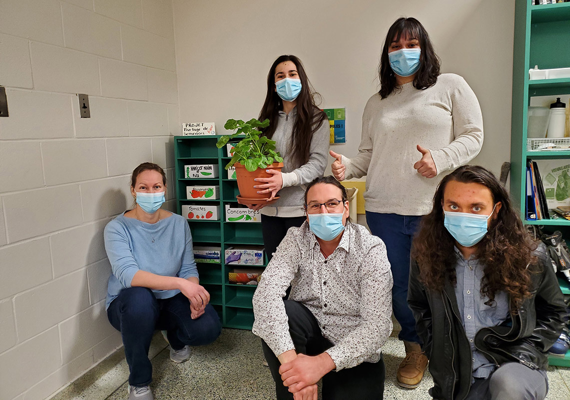 Cinq membre des comités environnementaux devant les étagères de partage de semences