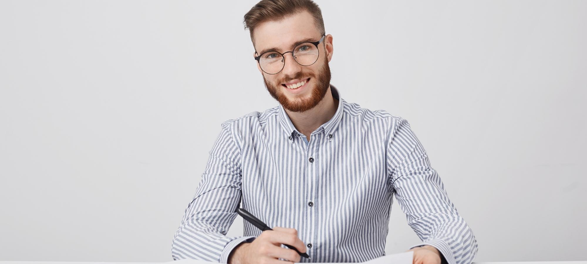 Un homme en chemise tient un stylo en souriant