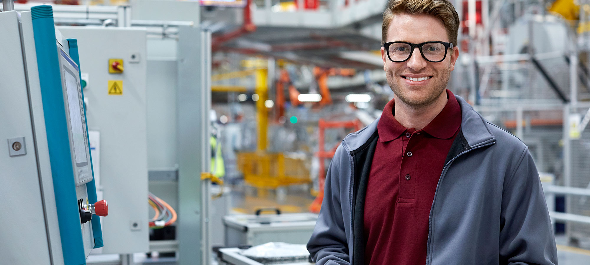 Photo d'un homme souriant dans une usine de production automatisée