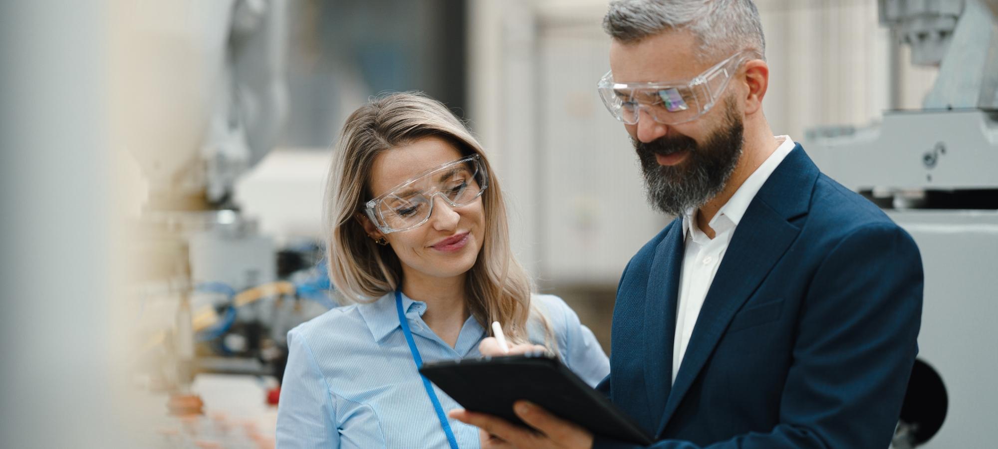 Une femme et un homme regardant l'écran d'une tablette dans une usine