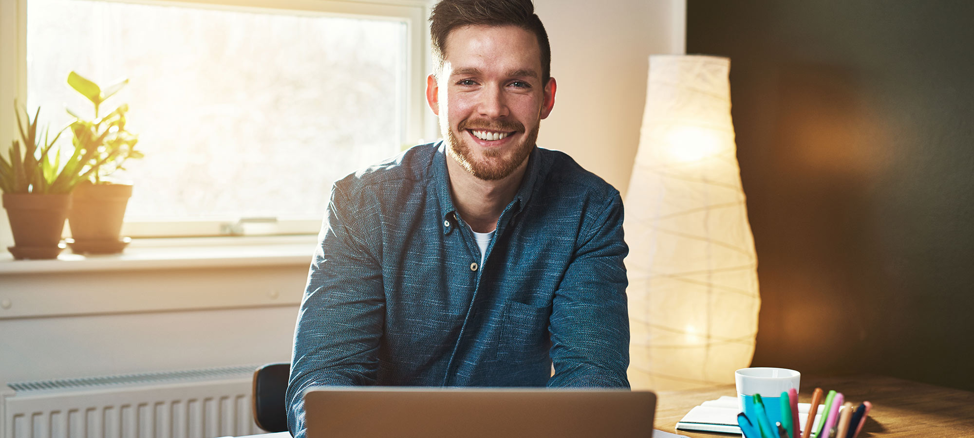 Homme souriant assis derrière un ordinateur portatif