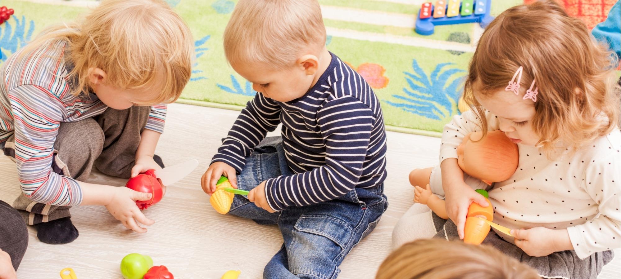 Trois jeunes enfants qui jouent assis au sol dans une garderie