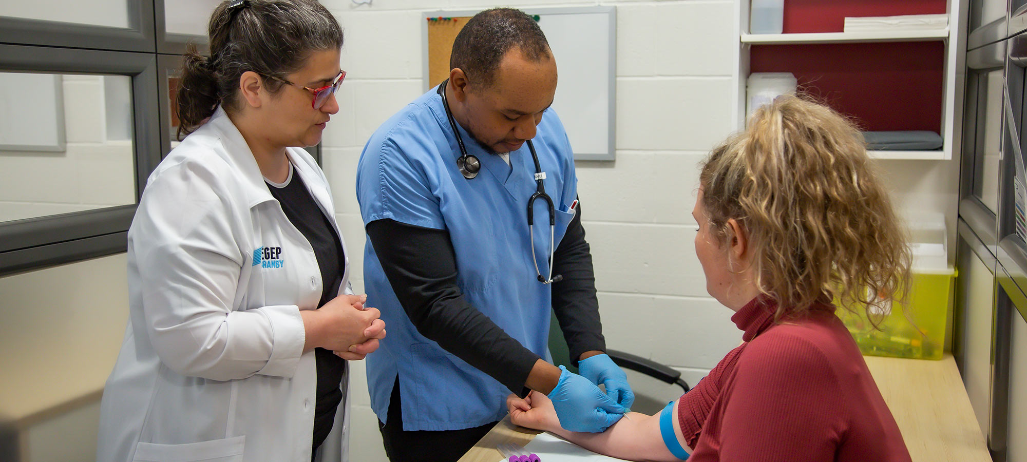 Photo d'une enseignante et d'un élève pratiquant une prise de sang à la clinique santé