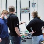 Un enseignant de génie électrique donne des conseils à deux étudiants