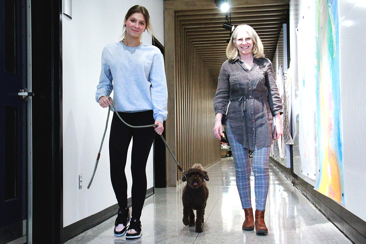 Deux femmes marchent dans un couloir avec un chien en laisse