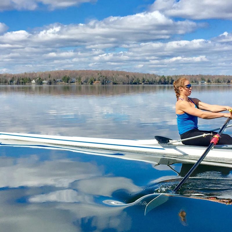 Sur un plan d'eau, une rameuse pratique l'aviron