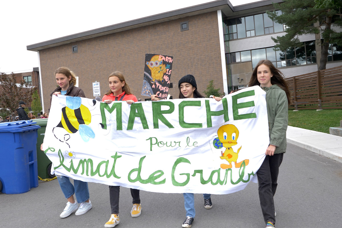 Quatre étudiantes à l'extérieur tenant la banderole Marche pour la climat de Granby