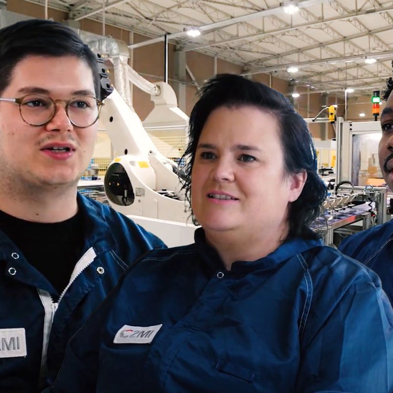 Trois techniciens portant un uniforme de travail bleu foncé