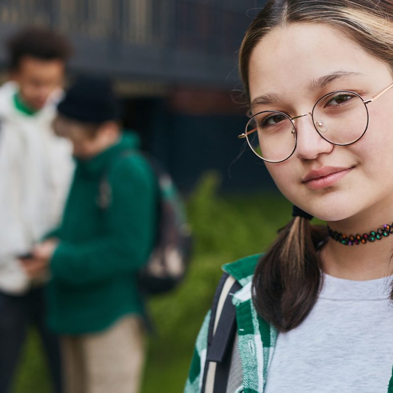 En avant-plan un adolescente avec des tresses, devant un trio de garçons