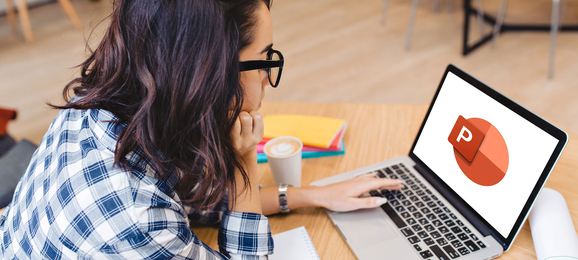 Une jeune femme regarde un écran où se trouve le logo de PoerPoint