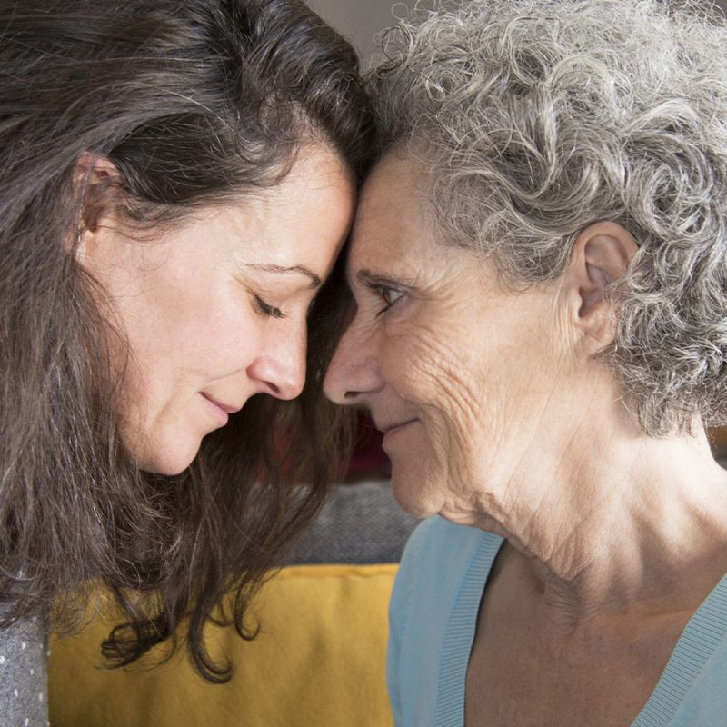 Une jeune femme et une dame âgée front contre front