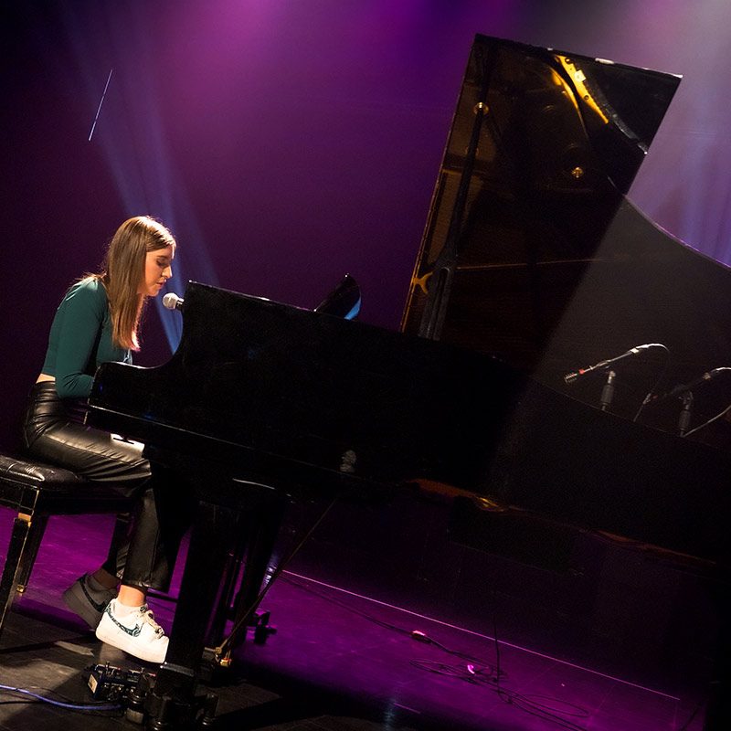 Charly-Ann Côté, gagnante du 1er prix, chante en s'accompagnant au piano sur la scène