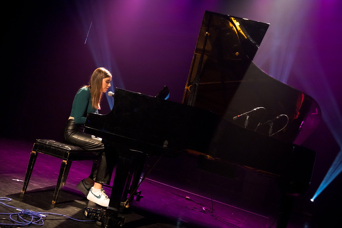 Charly-Ann Côté, gagnante du 1er prix, chante en s'accompagnant au piano sur la scène