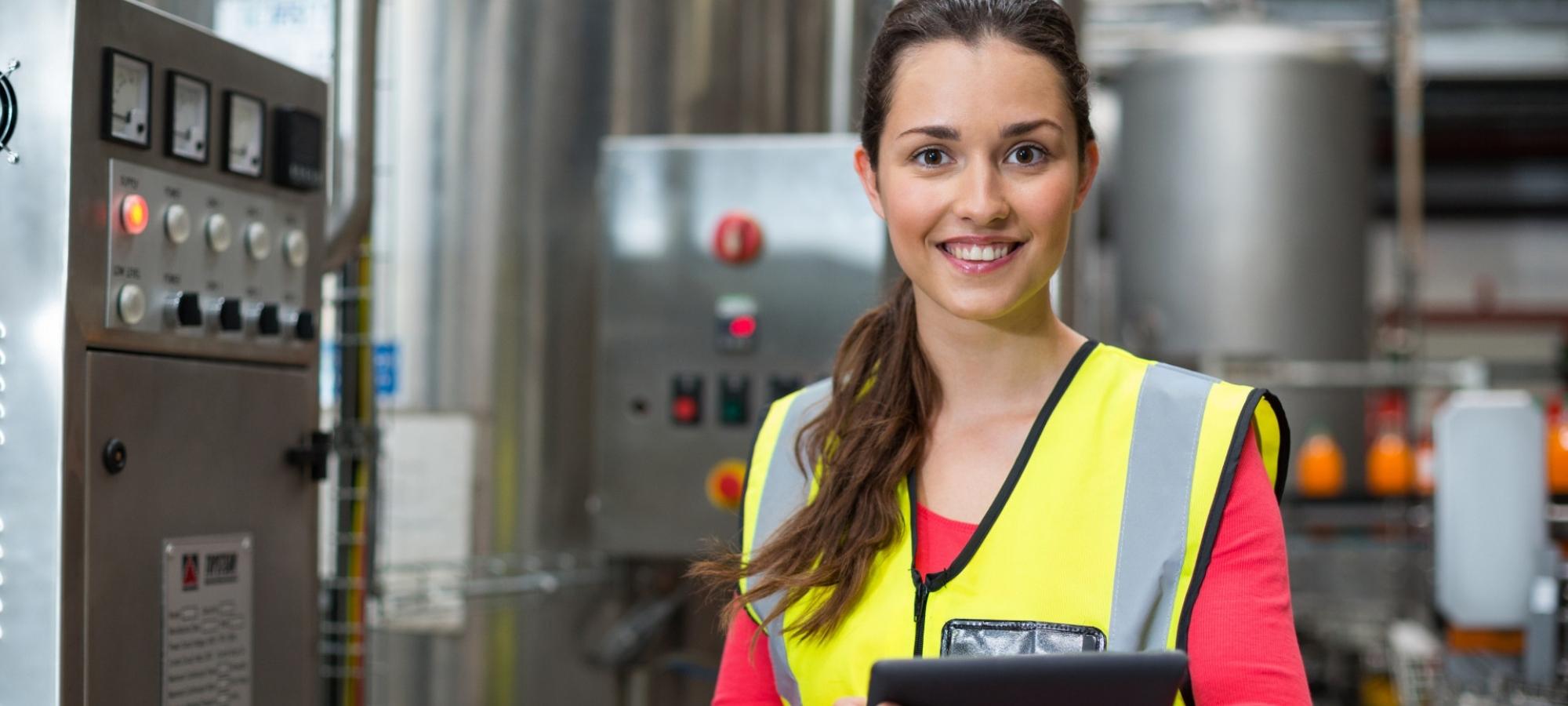 Une jeune femme avec une veste de sécurité devant un panneau de contrôle