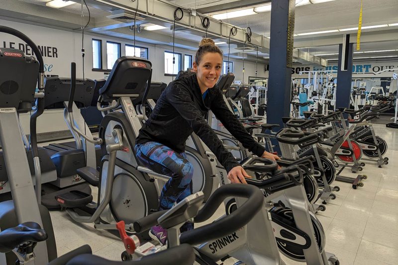 Une femme sur un vélo stationnaire dans un gym
