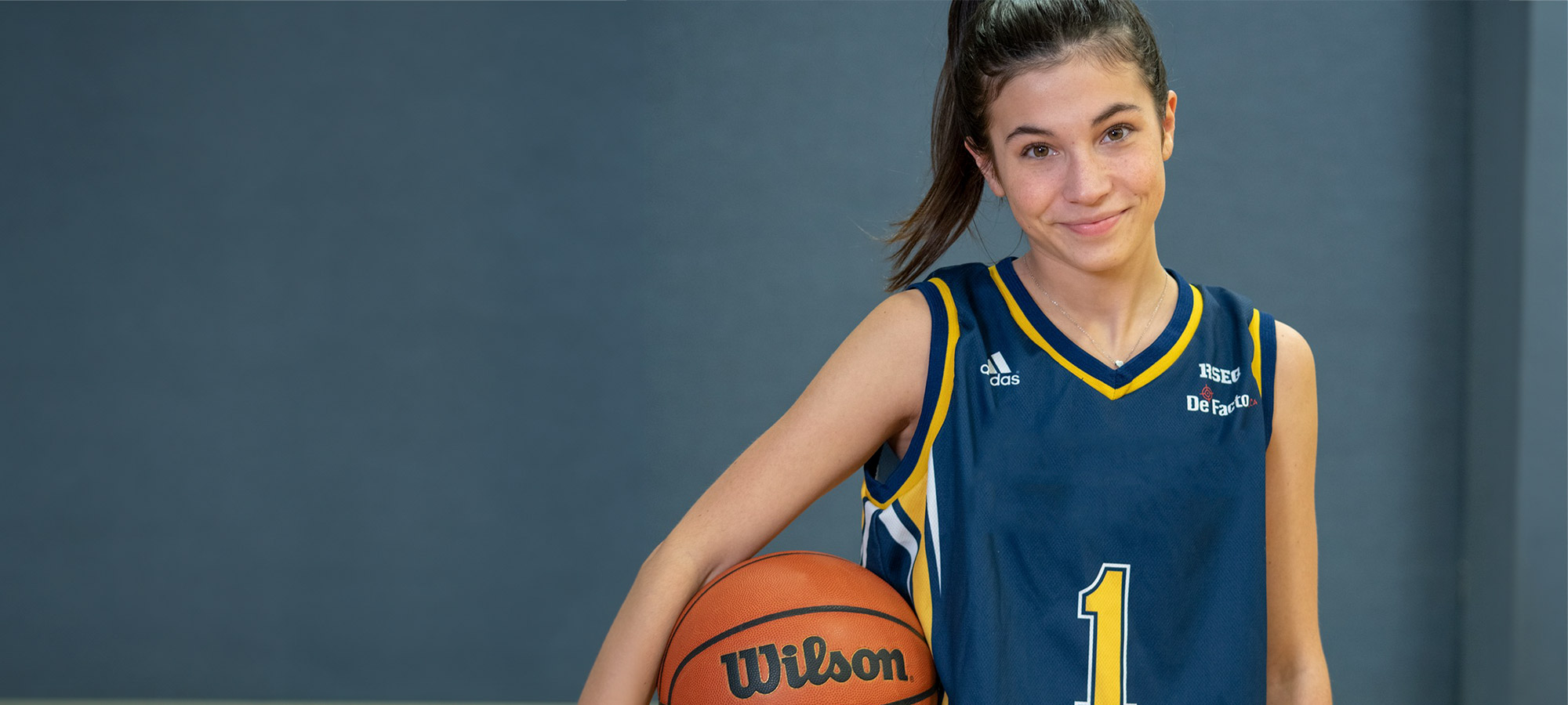 Une jeune joueuse de basketball en uniforme avec un ballon