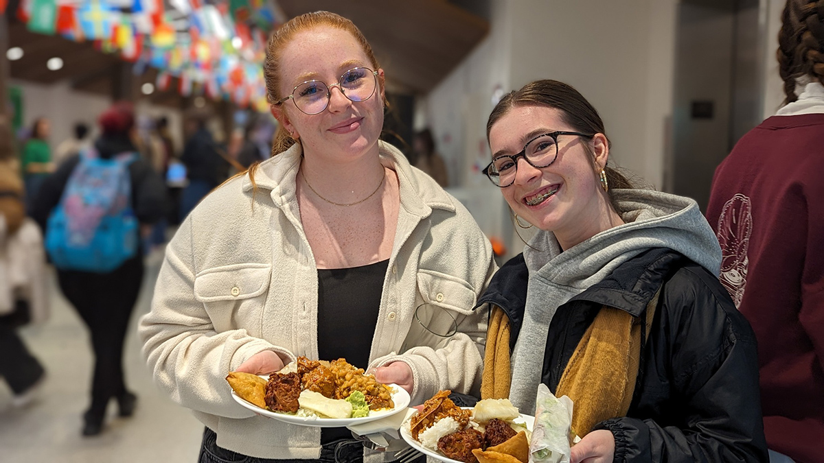 Deux étudiantes tenant des assiettes remplies de mets appétisants