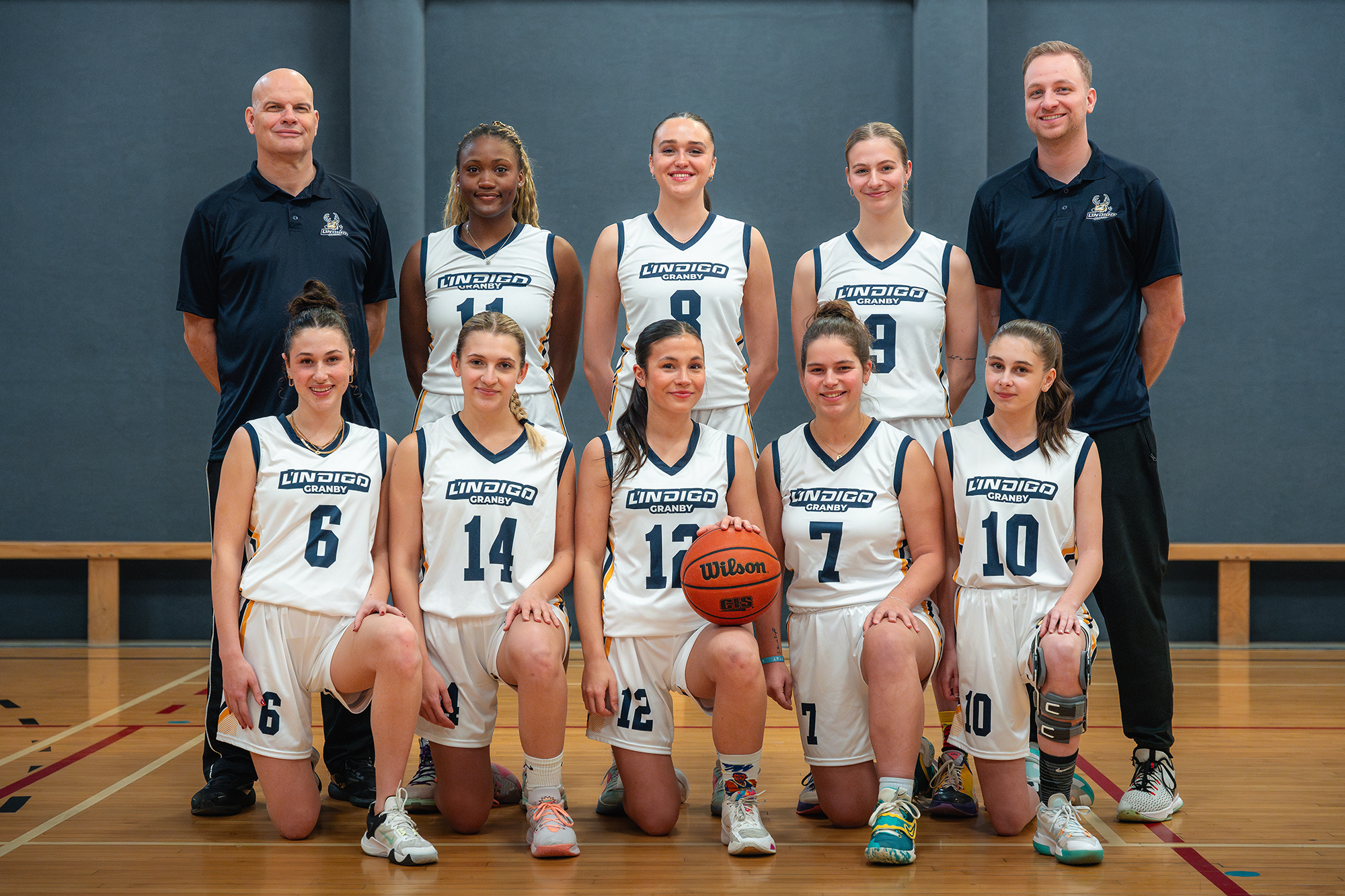 L'équipe de basketball féminin et entraîneurs en uniforme