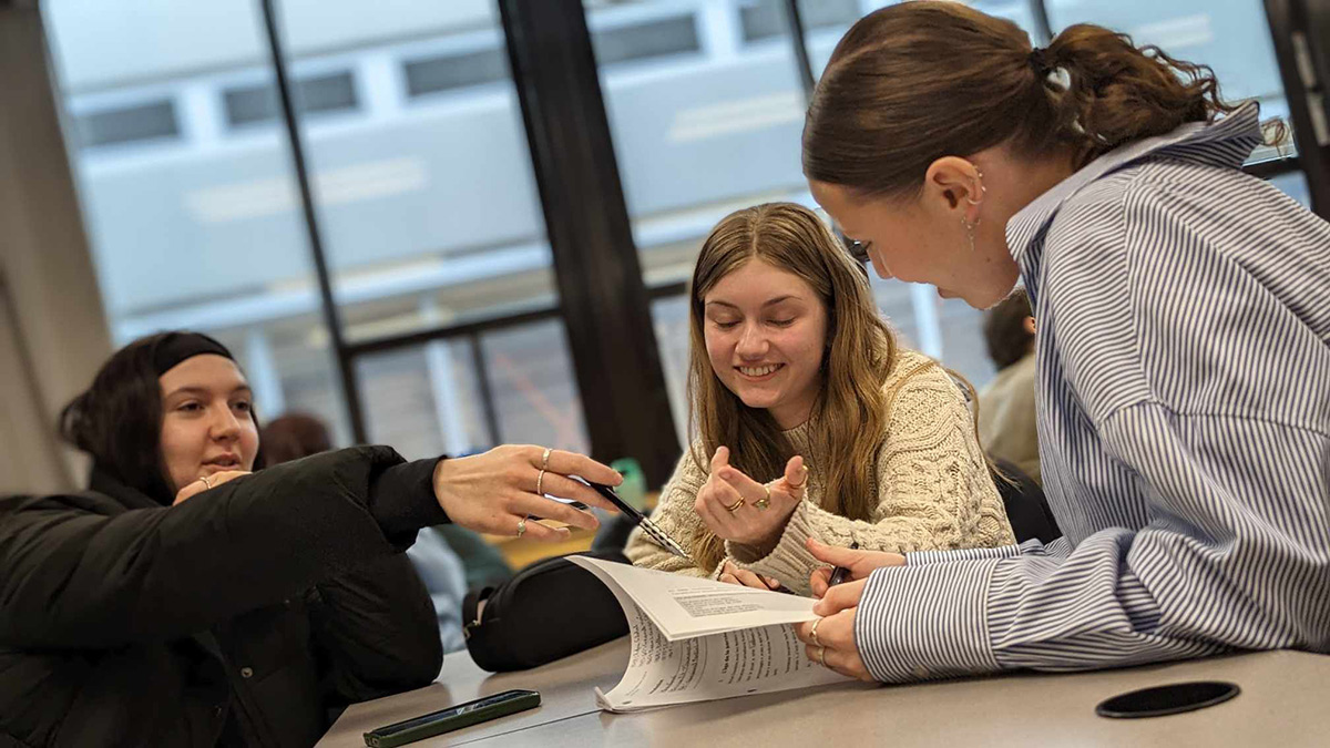 Trois étudiantes souriantes qui regardent un document