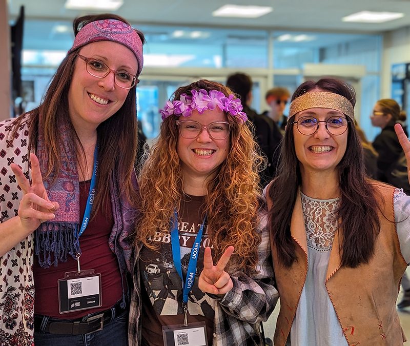 Trois jeunes femmes habillées en hippies font le signe de "Peace"