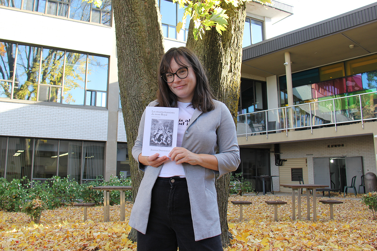 Une jeune autrice tient son livre dans un jardin à l'automne