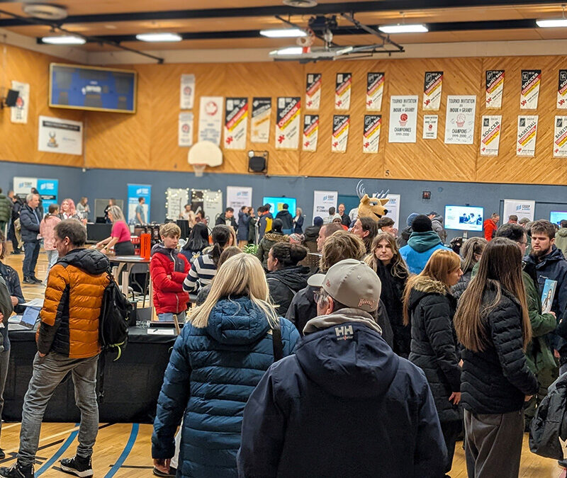 Vue d'un gymnase transformé en salon avec une foule de visiteurs