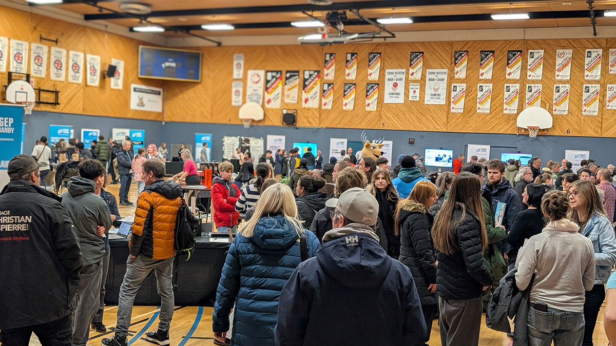 Vue d'un gymnase transformé en salon avec une foule de visiteurs