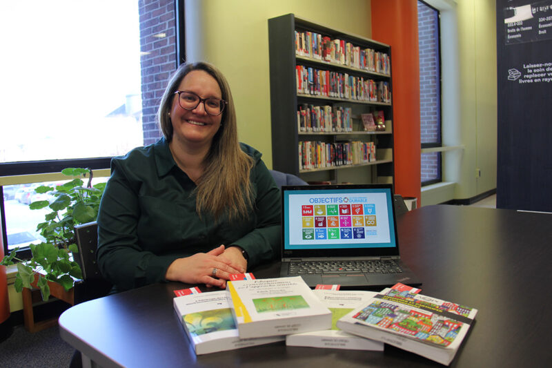 Un femme assise présente des livres et un site Web sur l'écologisation