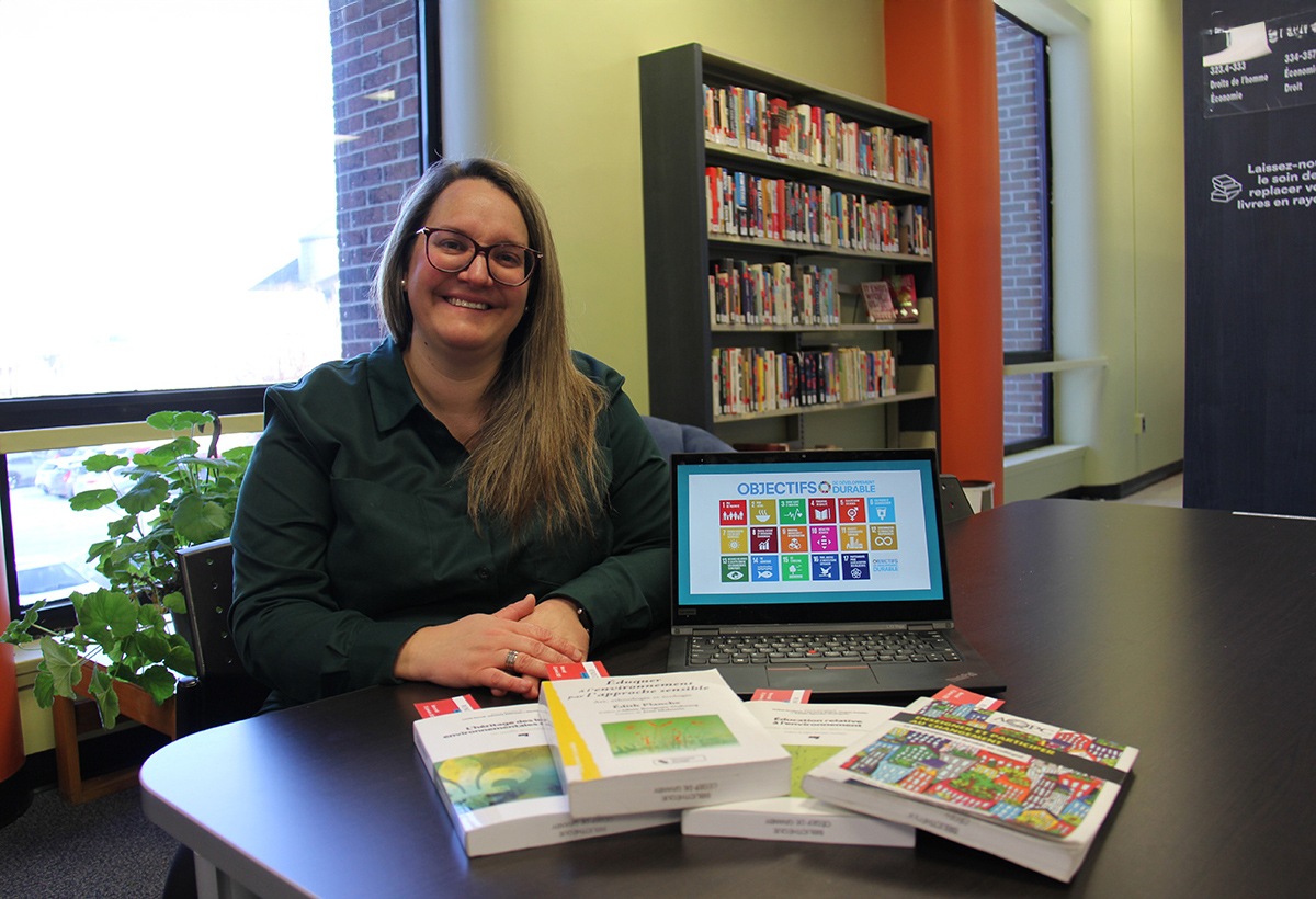 Un femme assise présente des livres et un site Web sur l'écologisation