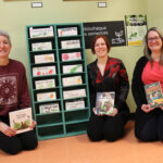 Trois femmes à côté d'une bibliothèque de semences