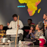 Personnes africaines assises sur une scène parlent au public
