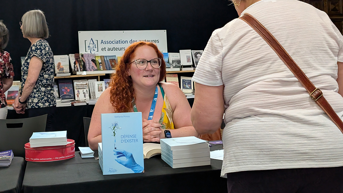 Une autrice à son kiosque dans un salon du livre
