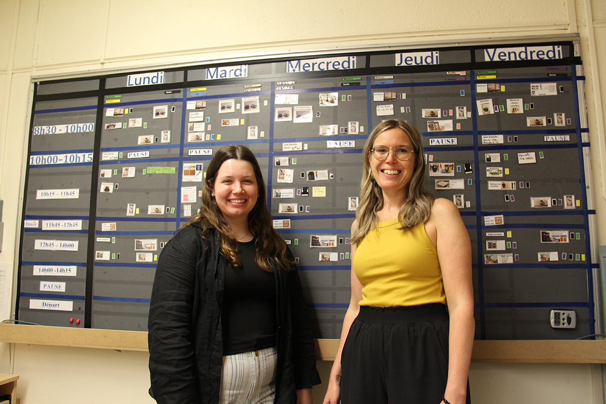 Deux jeunes femmes devant un tableau où est afficher un horaire