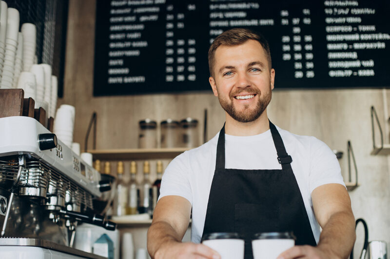 Un barista tient deux cafés dans ses mains