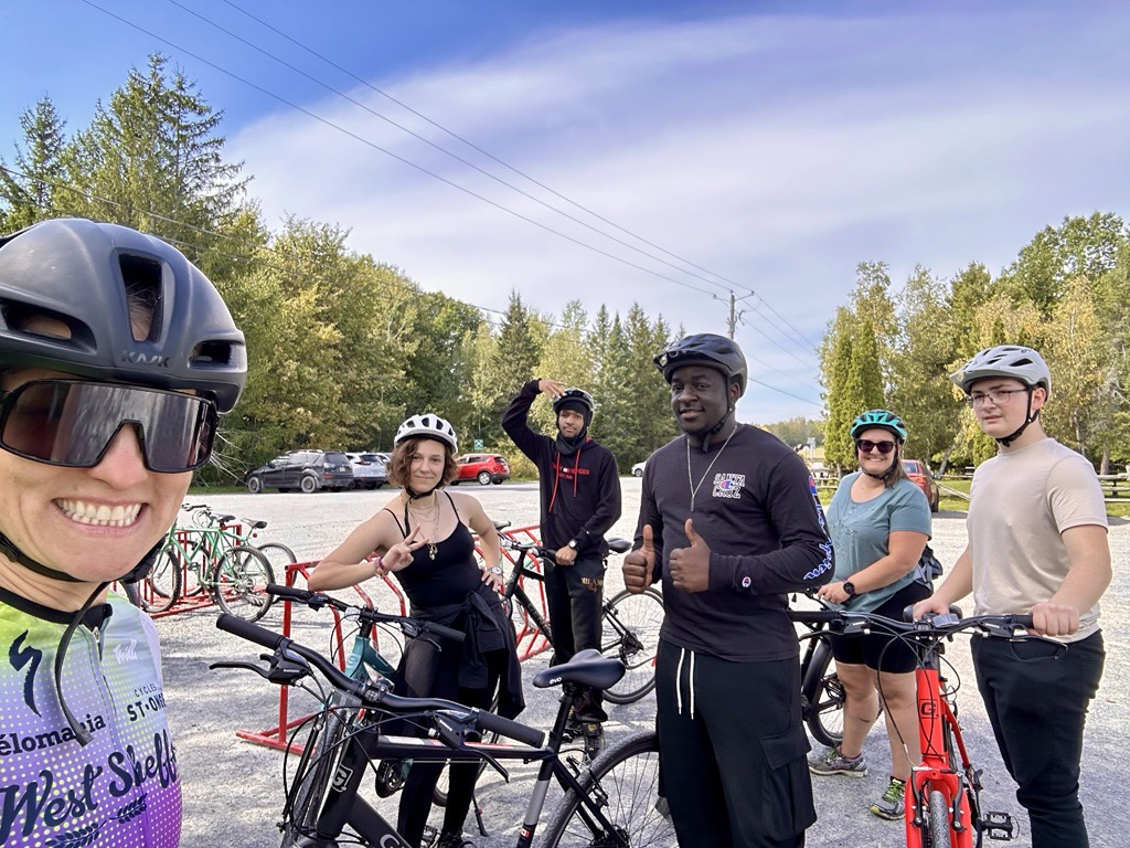 Six cyclistes sur une piste cyclable entourée d'arbres
