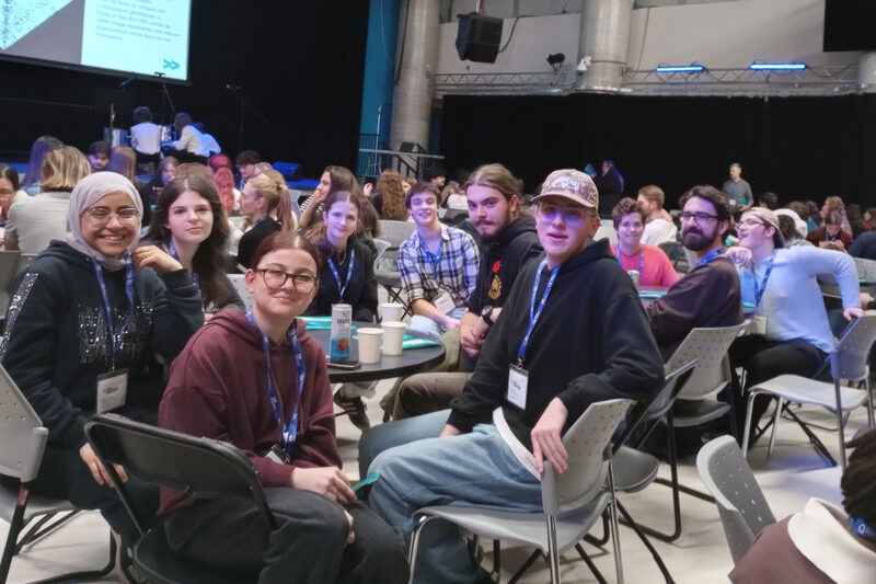 Des personnes assises autour d'une table dans une salle bondée