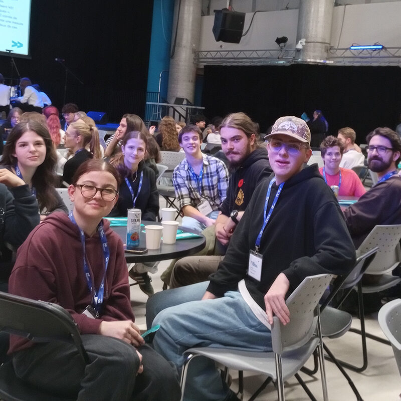 Des personnes assises autour d'une table dans une salle bondée