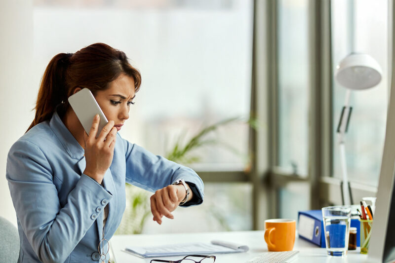 Une femme au téléphone regarde sa montre