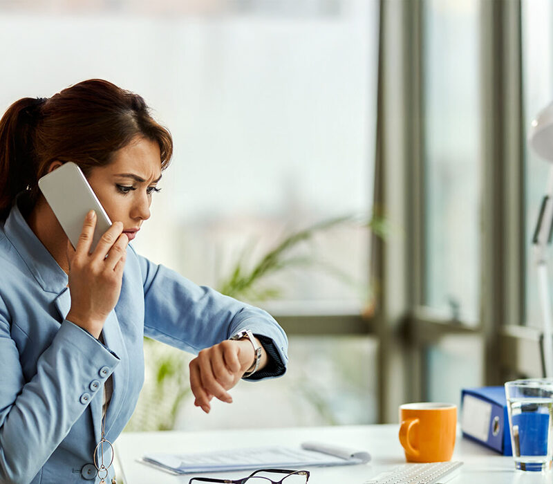Une femme au téléphone regarde sa montre