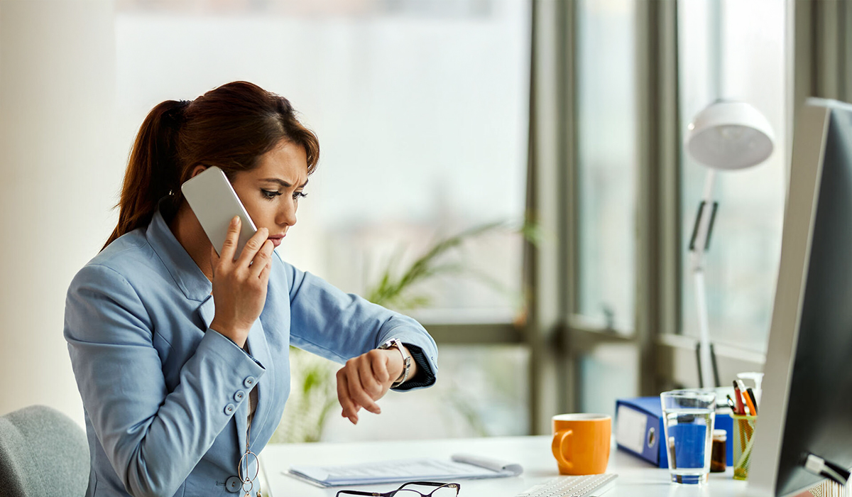Une femme au téléphone regarde sa montre