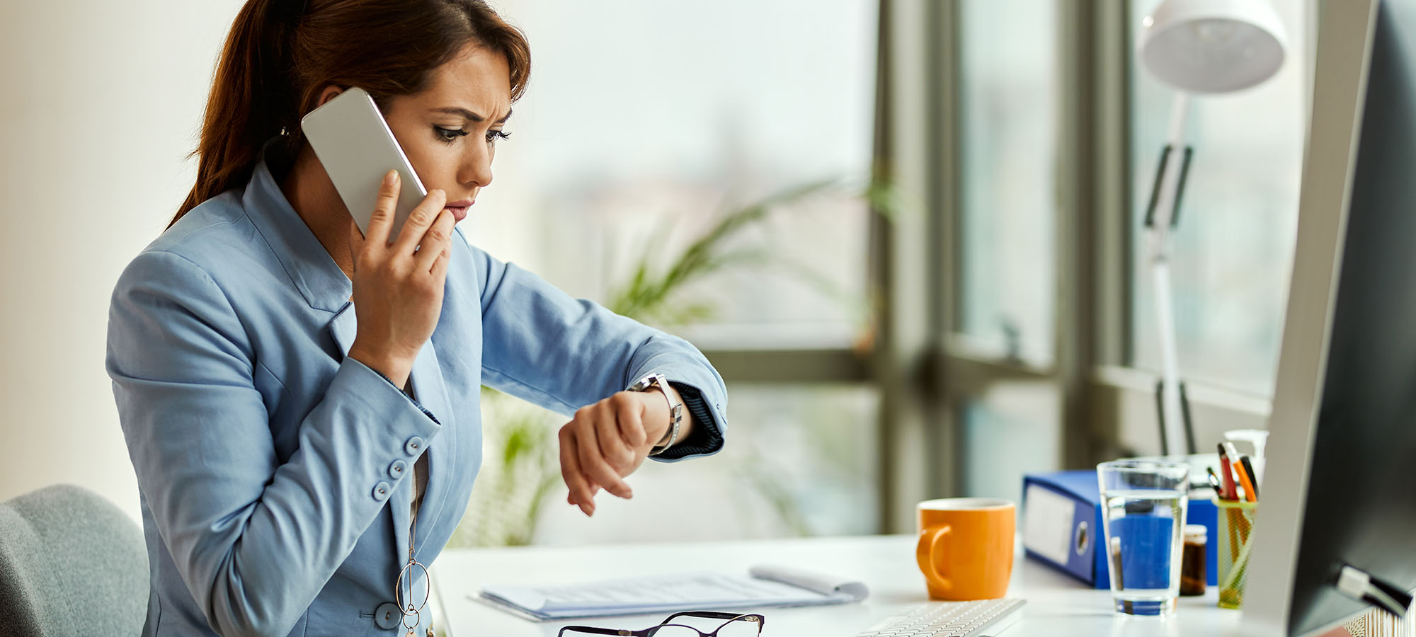 Une femme au téléphone regarde sa montre